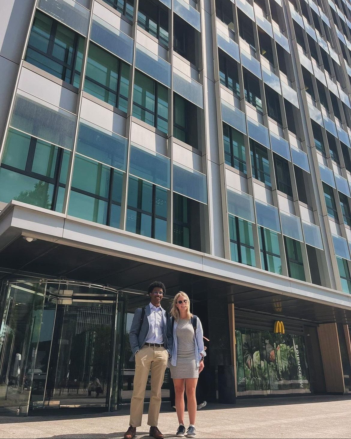 two students in business clothing outside of a modern tall building
