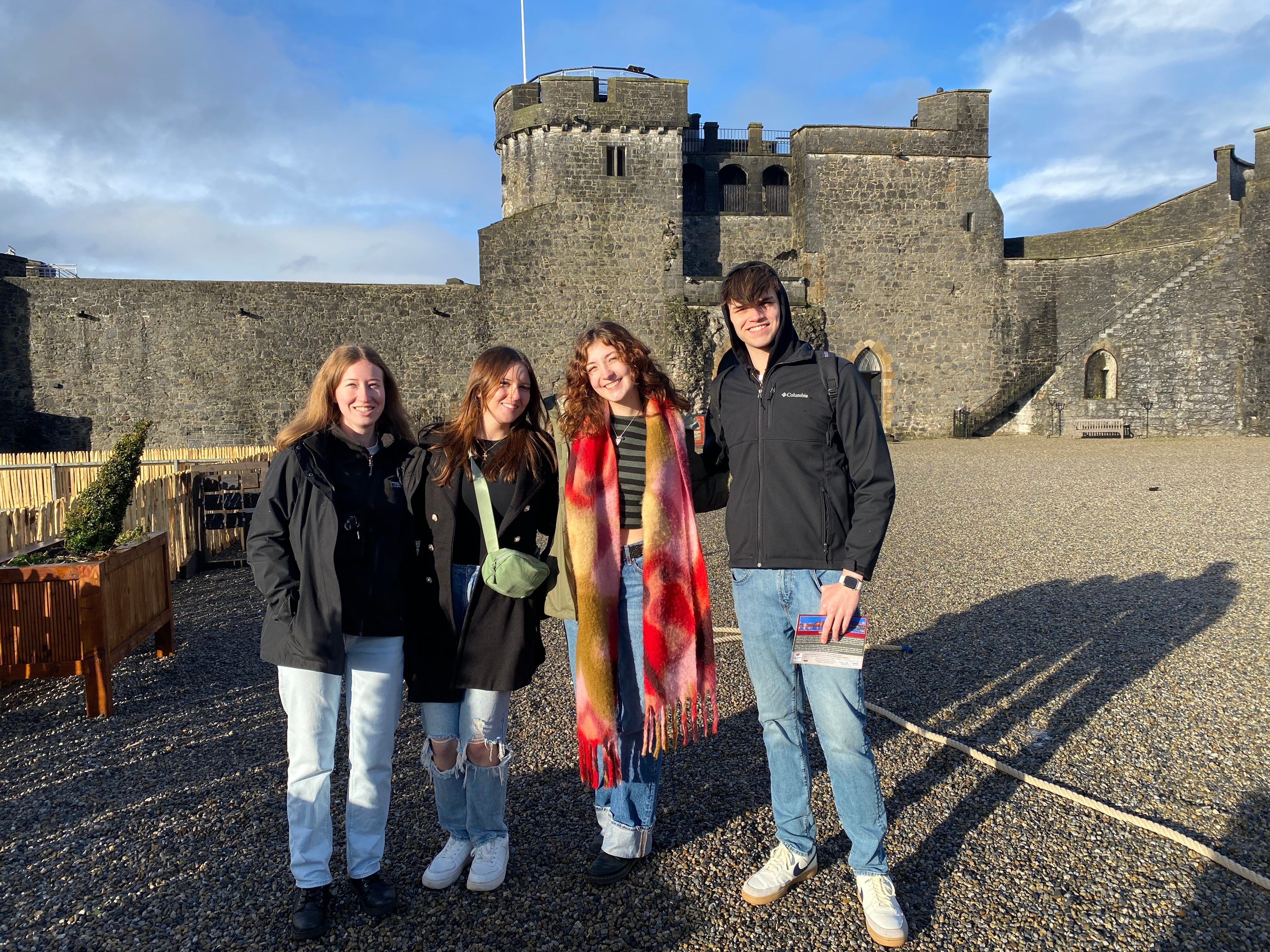 four students smiling in front of a castle